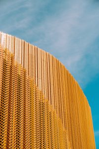 a tall yellow building with perfored walls against a blue sky